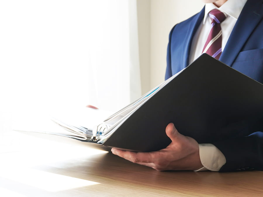 バインダーの書類を確認していく、事務所代表の男性の手元