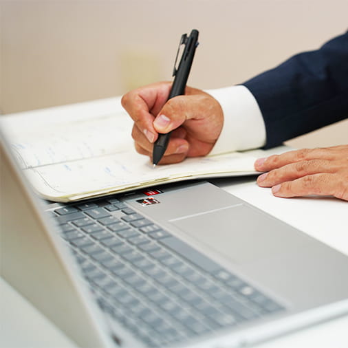 手帳に予定を書きこむ男性の手元