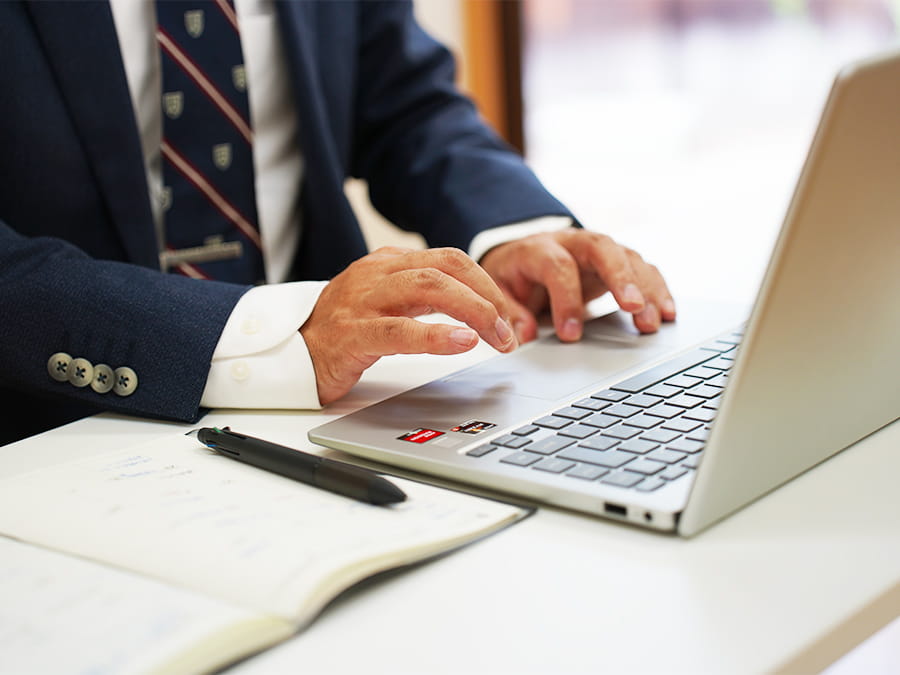 手帳を横に置き、予定を確認しながらパソコンを操作する事務所代表の手元