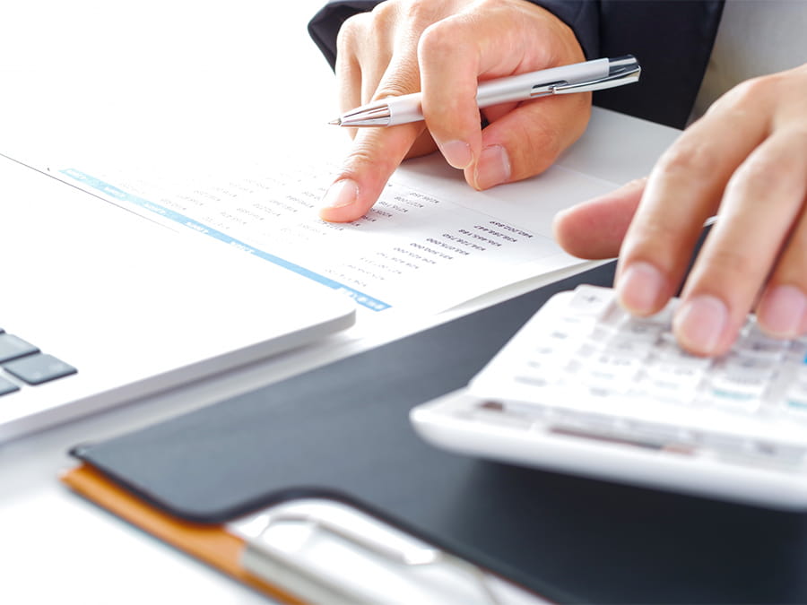 数字が書かれた資料を見ながら、電卓を操作していく男性の手元